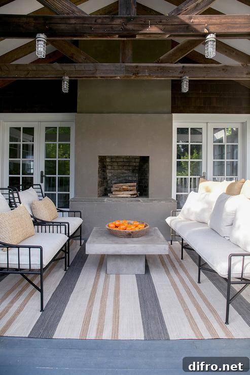 Striped outdoor rug with a concrete table centered between wrought iron seating under industrial-style lights.