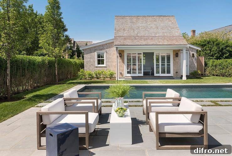 Concrete pavers beside an in-ground pool with teak chairs and a slim coffee table.