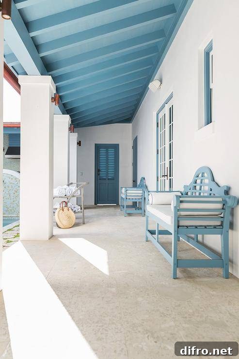 Cottage covered patio with a blue wooden bench under a blue plank ceiling.