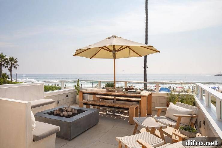 An l-shaped concrete sofa with gray cushions sits at a gray fire pit on a beach cottage patio.