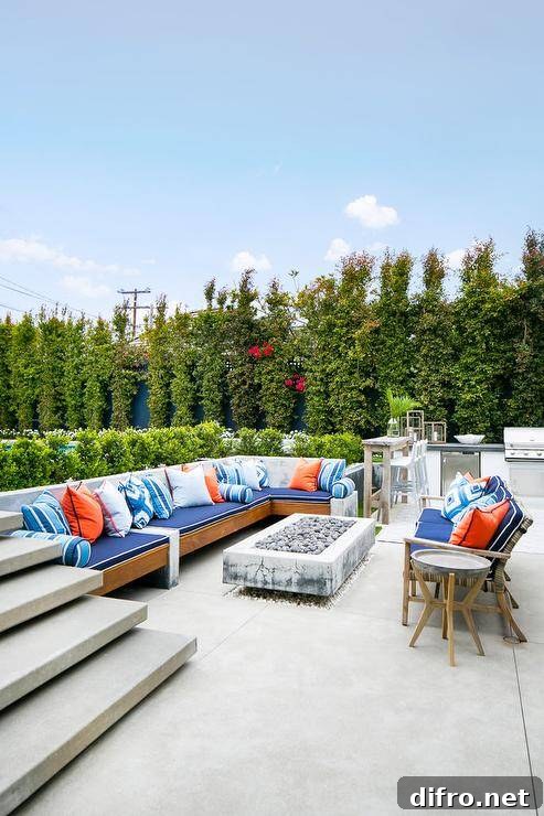 Cottage outdoor patio space furnished with a teak outdoor sectional accented with blue and orange accent pillows and a rectangular concrete fire pit.