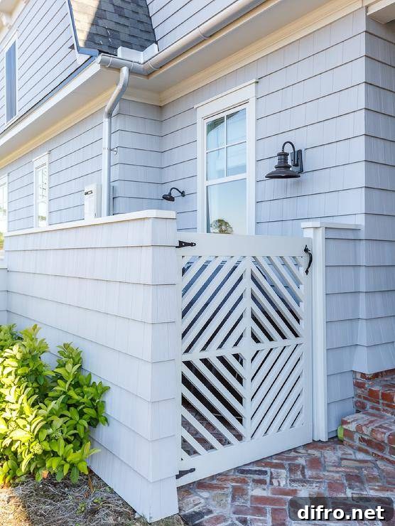 This lovely gray shingled home is accented with red brick herringbone pavers leading throw a white wooden gate.