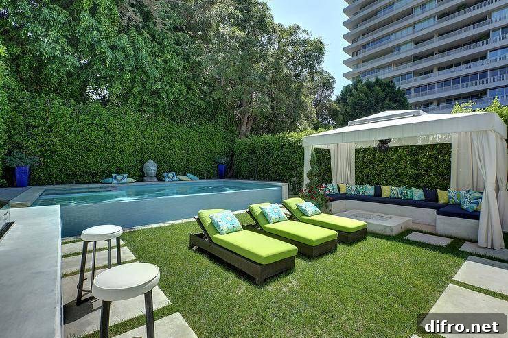 Modern above ground pool featuring a Buddha statue beside wicker sun loungers with lime green cushions. A cabana adds to the backyard design with a concrete sectional and fire pit.