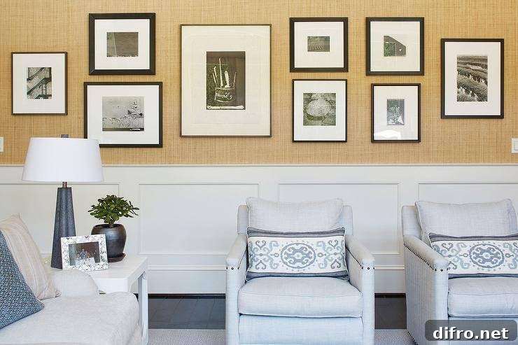 Gallery wall on textured wallpaper above wainscoting in a living room.