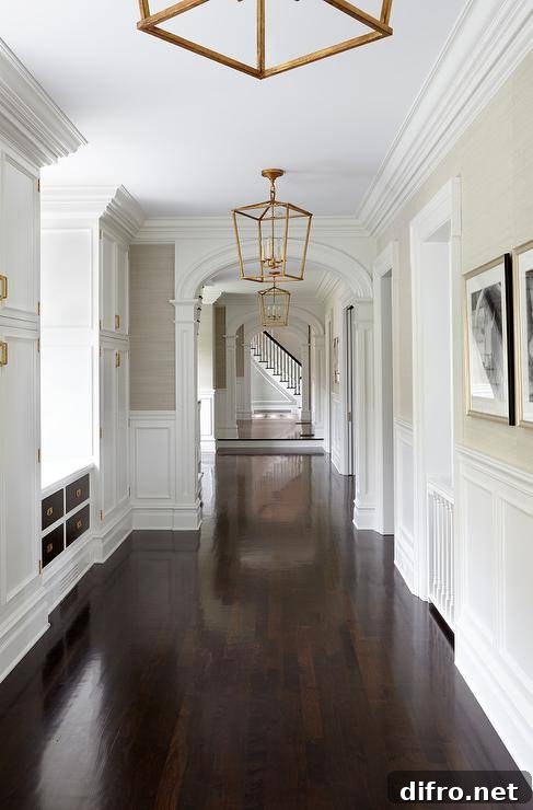 long hallway with gold chandeliers white trim wainscotting and dark walnut floors