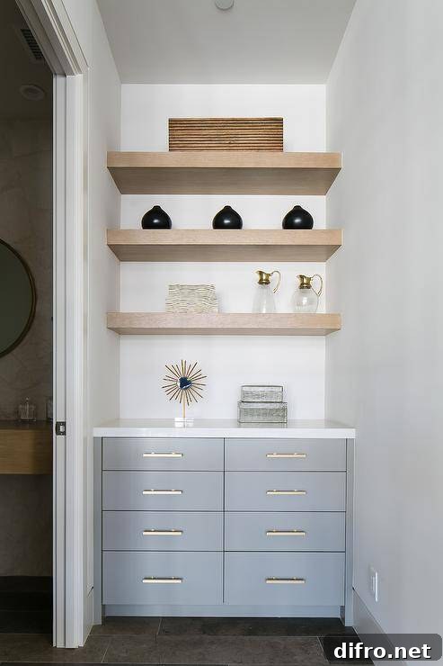 Bathroom hallway fitted with gray cabinets and stacked floating shelves