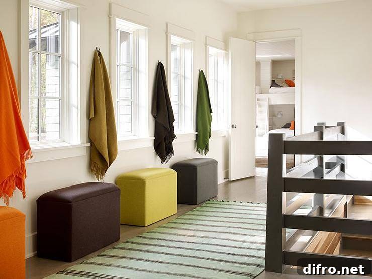 Country home hallway features a row of hooks draped in earth toned colored throw blankets over storage ottomans