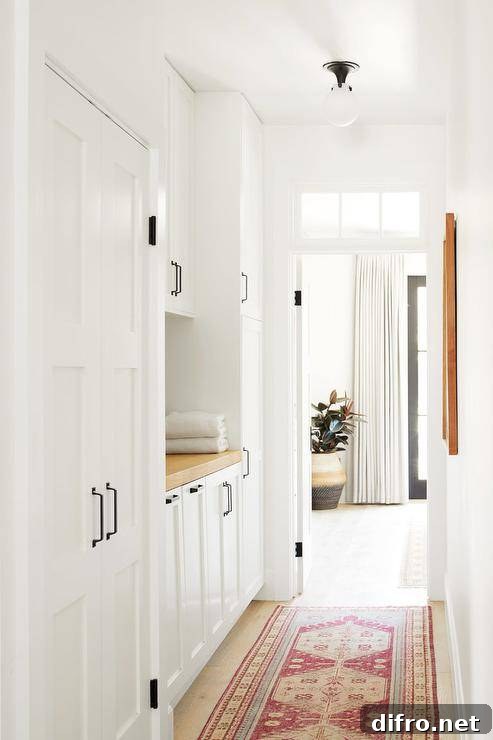 Hallway laundry room designed with a butcher block countertop and white cabinets
