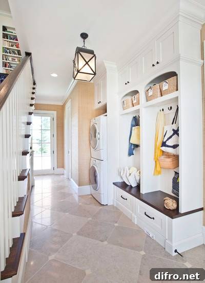 Mudroom area with built-in arched cubbies, bench and drawer storage with a stackable washer and dryer