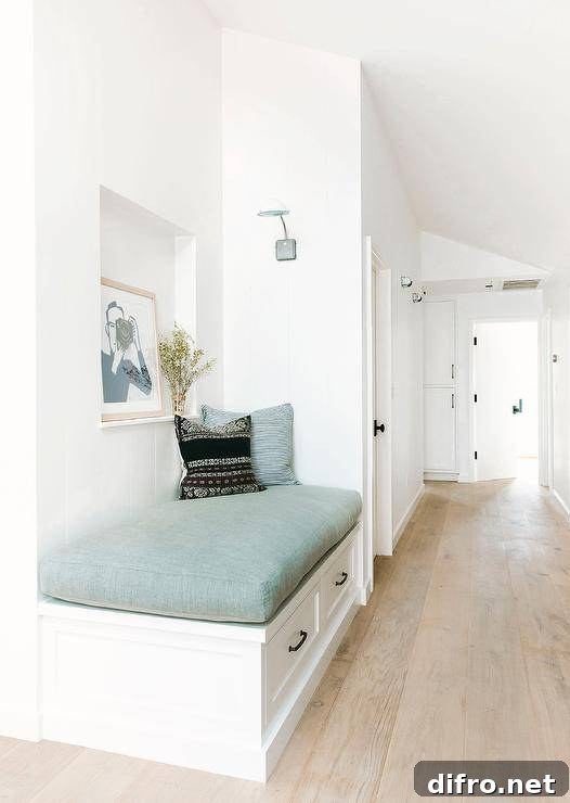 A white built-in foyer reading bench is fitted with drawers and topped with a blue seat cushion