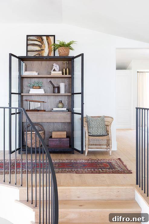 A red vintage rug sits in front of a woven accent chair placed beside a hallway cabinet