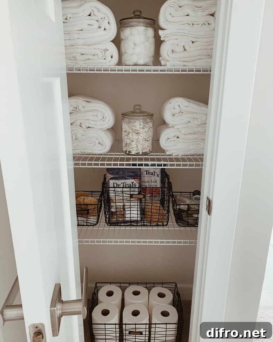 wire shelving in bathroom closet with folded towels apothecary jars wire baskets with toilet paper