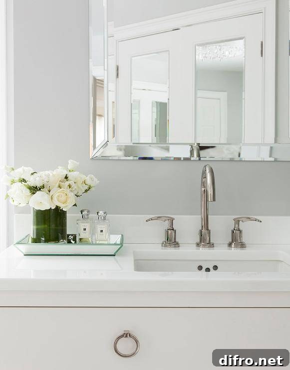 A beveled mirrored tray filled with white roses and fragrance bottles.