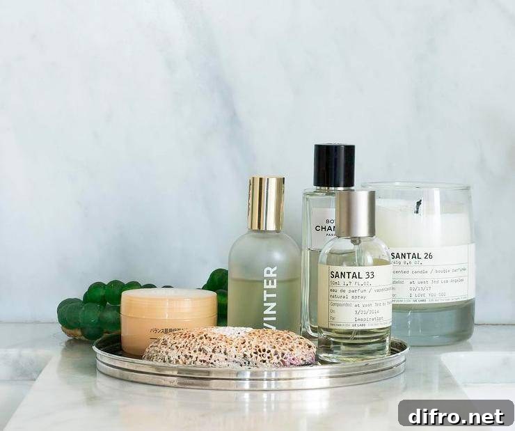 Round perfume tray displaying designer perfumes and skincare essentials on a marble countertop in a transitional bathroom space.