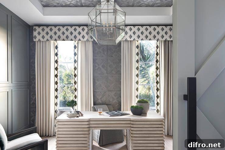 Elegant home office with a gray desk paired with a gray slipper chair between windows dressed in white curtains with black diamond trim.