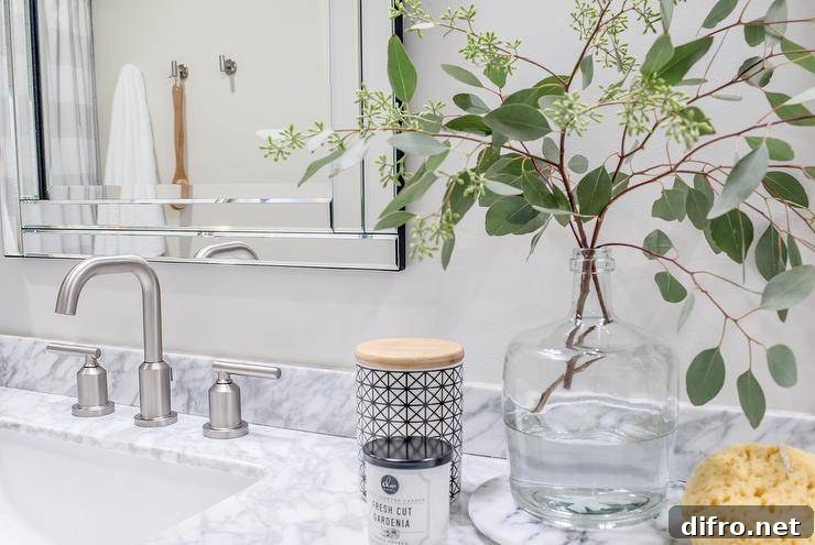 Modern nickel faucets compliment gray marble countertop and styled countertop accessories.