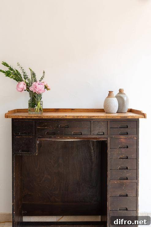 Workspace features vintage wooden desk with drawers.