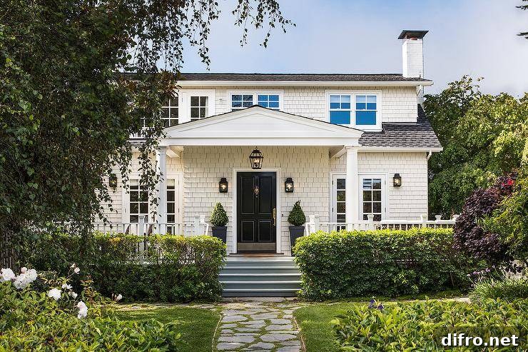 White cottage home with a black front door and classic porch columns.