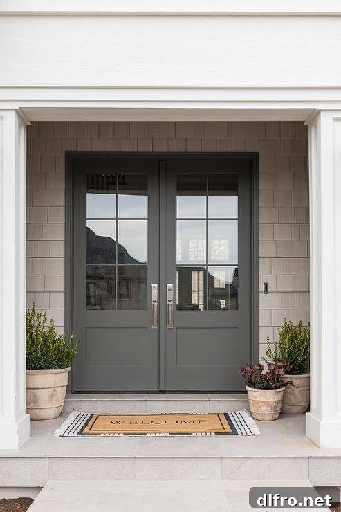 Styled front porch features layered welcome mats and potted plants.