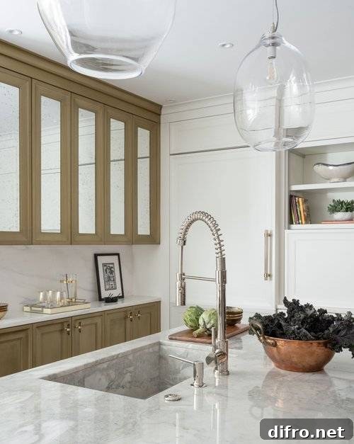 A pull-out faucet is fixed to a gray marble kitchen island countertop over a gray marble sink in a beautifully appointed kitchen.