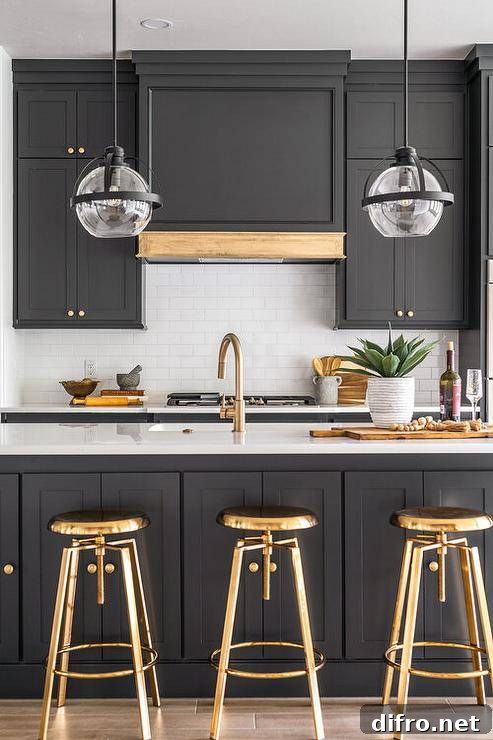 Black and white kitchen features brass swivel stools at a black island with gold gooseneck facuet.