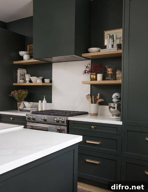 Black and white kitchen features blond floating shelves, a black hood over a white marble slab backsplash and black cabinets with brass pulls.