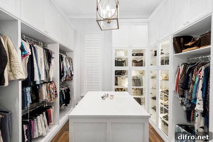 Spacious custom walk in closet features lighted purse cabinets and a white island.