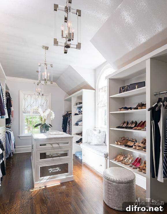 Sun-filled walk-in closet with window seat and mirrored drawers on the island.