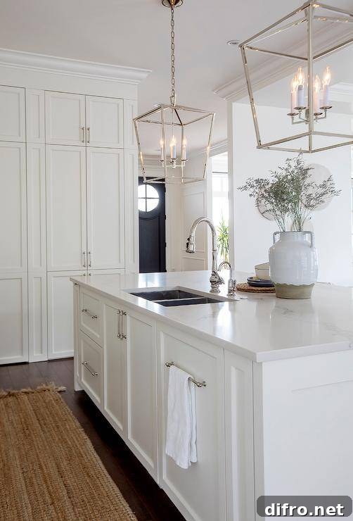 Lanterns hang over a white center island fitted with a stainless steel dual sink and a polished nickel gooseneck faucet.