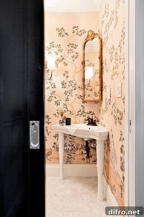 Pink-chinoiserie bathroom with corner pedestal sink and gold ornate mirror