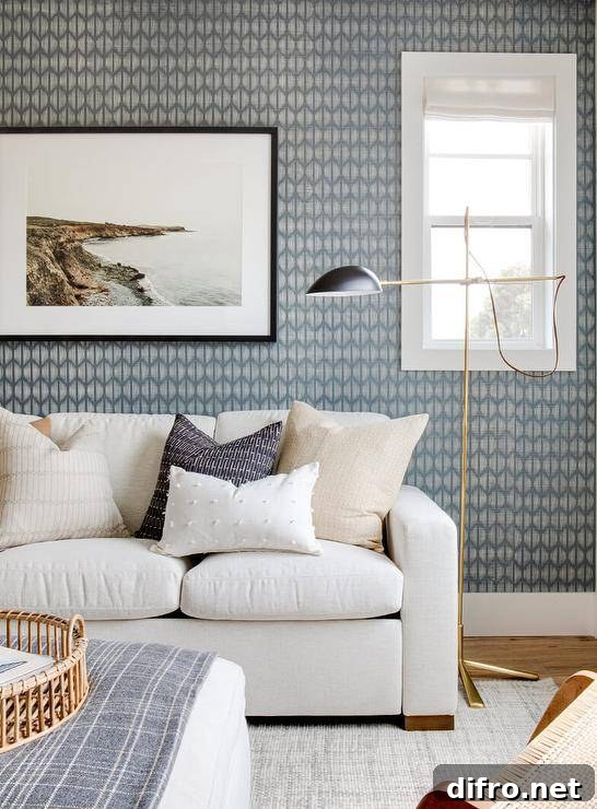 Living room features a white modern couch with tan accent pillows on a gray jute rug illuminated by a brass floor lamp and blue gray wallpaper.
