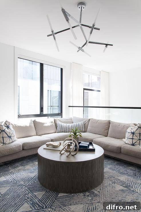 Tan corner sectional with tan and blue pillows on a tan and blue wool rug facing a round black coffee table.
