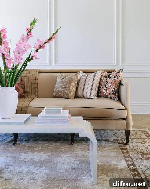 Beige sofa finished with brass nailhead trim and pink pillows in a styled living room.
