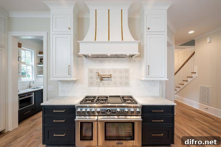 White and gold chimney-style range hood over a mosaic cooktop backsplash