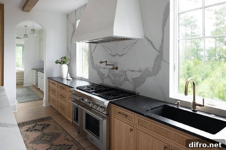 White plastered hood between windows over a stainless range and pot filler