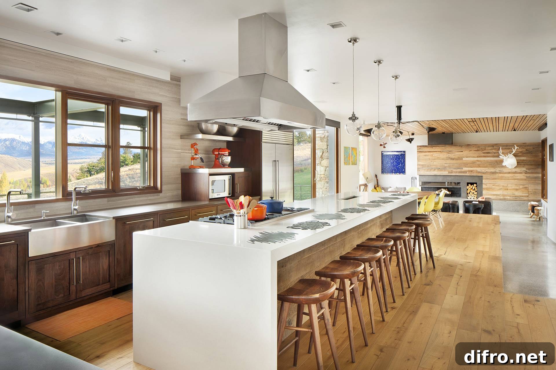 bright kitchen with large window over sink, white kitchen island with light wood stools and silver stove range hood