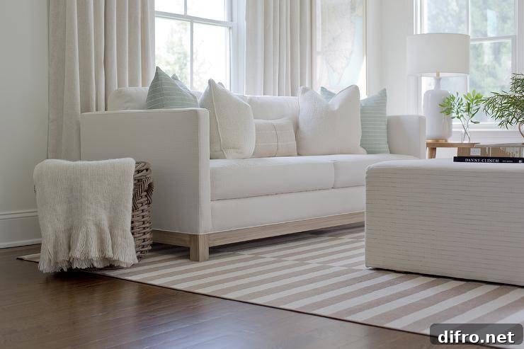 Living room features a white shelter back couch with light blue stripe pillows and a cream throw blanket