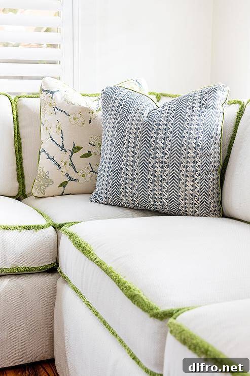 Close-up of green fringe trim and blue and white accent pillows on a white sectional