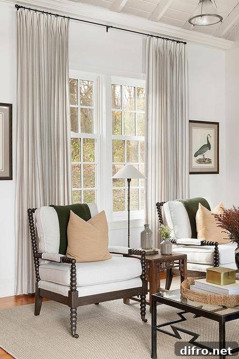 Cottage living room with black spindle chairs and green throws in front of light curtains