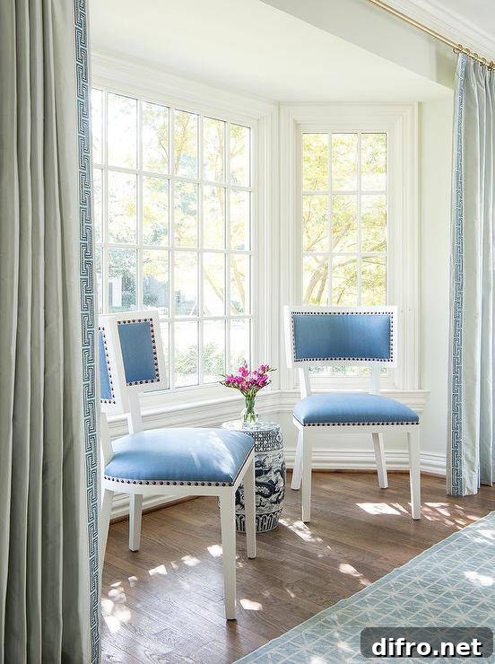 Blue velvet dining chairs sit in a bay window nook flanked by blue Greek key curtains.
