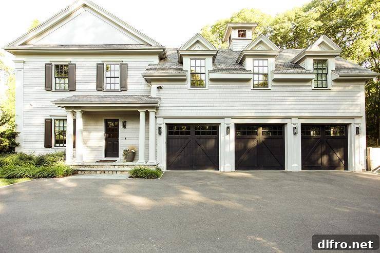 Light gray shake siding home boasting a black front door, two-car garage, and gray shutters with doric columns. The covered porch and greek columns invite a stunning curb appeal to the home property.