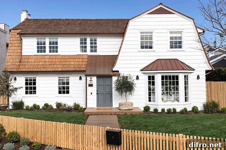 A charcoal gray front door accents a white lap cottage home finished with a gorgeous shingles roof.