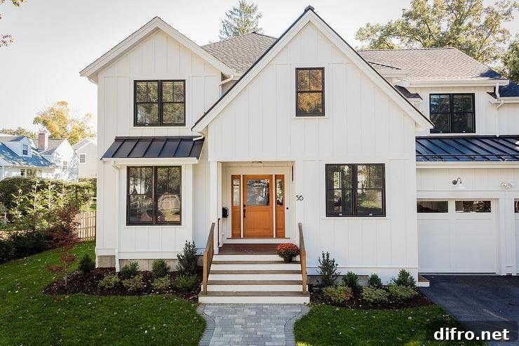 A gray brick pavers lead to a black and white craftsman style home accented with modern numbers and white board and batten siding.