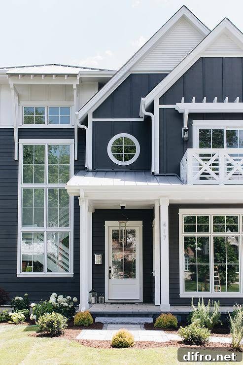 White and dark navy blue house boasting white trim and farmstyle appeal with an x trim balcony accented with various siding.