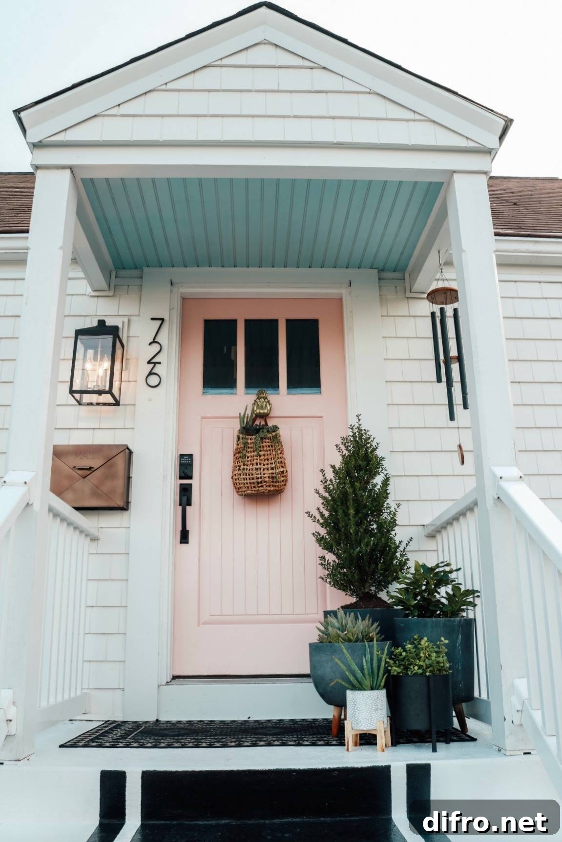 pink front door with large plants on porch and hanging basket on door