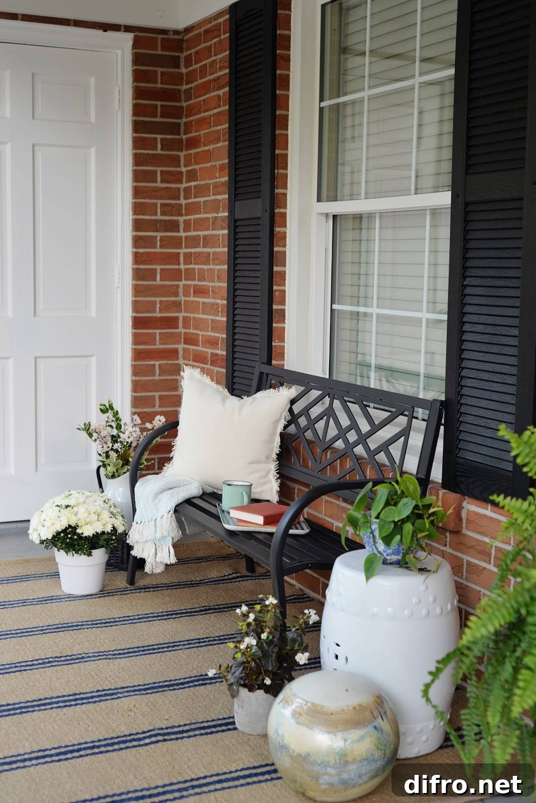 black wrought iron bench with pillow and book surrounded by plants on front porch
