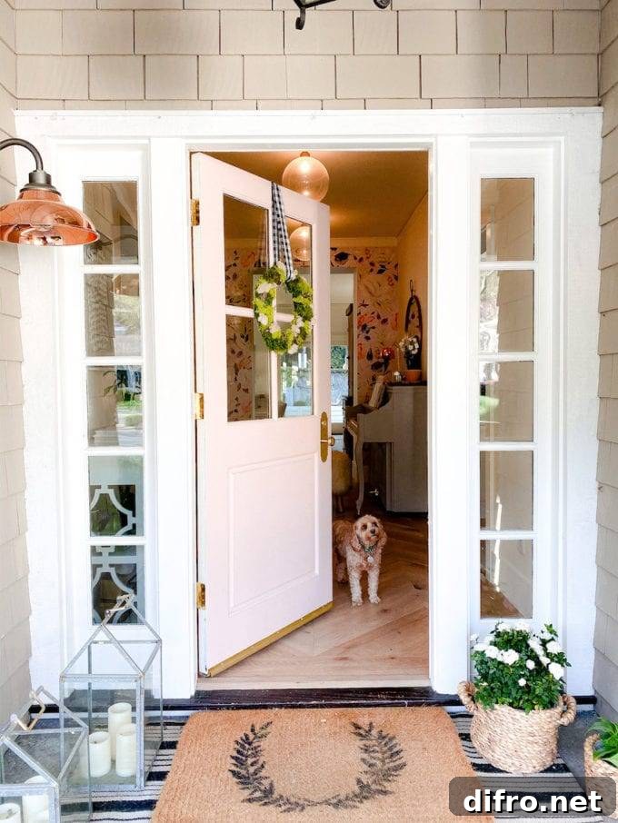 front porch with welcome mats and lanterns on ground, door open to show small dog