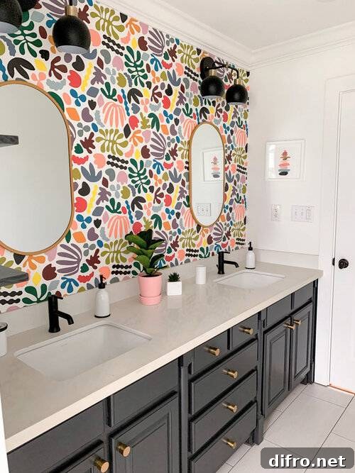 multicolored assorted shapes on bathroom wallpaper with black cabinets and gold mirror