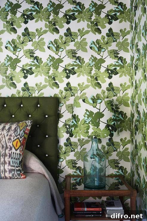 Green floral wallpaper behind a bed with a green tufted headboard