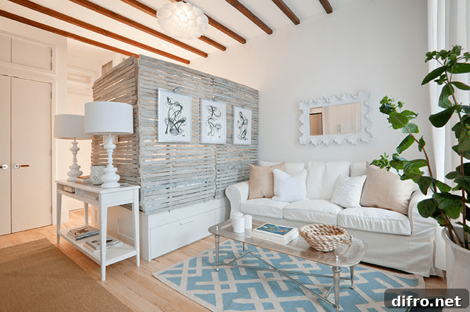 Studio apartment with white sofa and partition wall placed around bed frame to create cozy bedroom space.